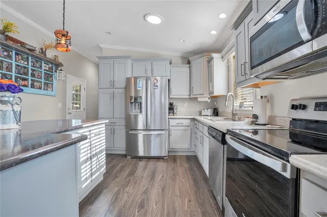 a kitchen with stainless steel appliances granite countertop a refrigerator a stove a sink dishwasher and a refrigerator with wooden floor