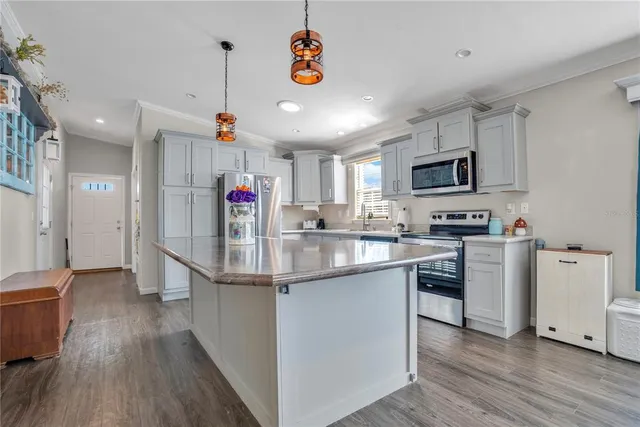 a kitchen with kitchen island granite countertop a sink cabinets and stainless steel appliances