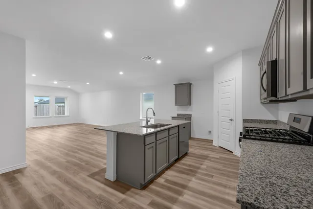 a kitchen with stainless steel appliances granite countertop a stove a sink and a refrigerator