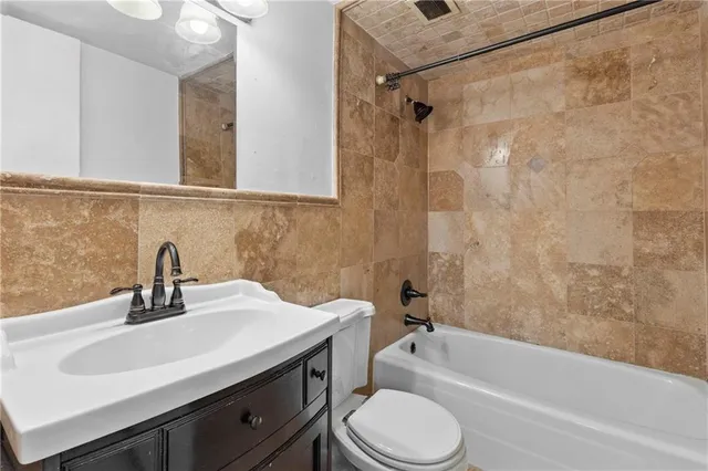 a bathroom with a bathtub shower sink vanity mirror and toilet