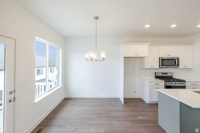 4816 Heartwood Road, Unit 423 Mapleton, UT 84664 - Photo 7 of 21 Kitchen with white cabinets, stainless steel appliances, light wood-type flooring, and suspended lighting