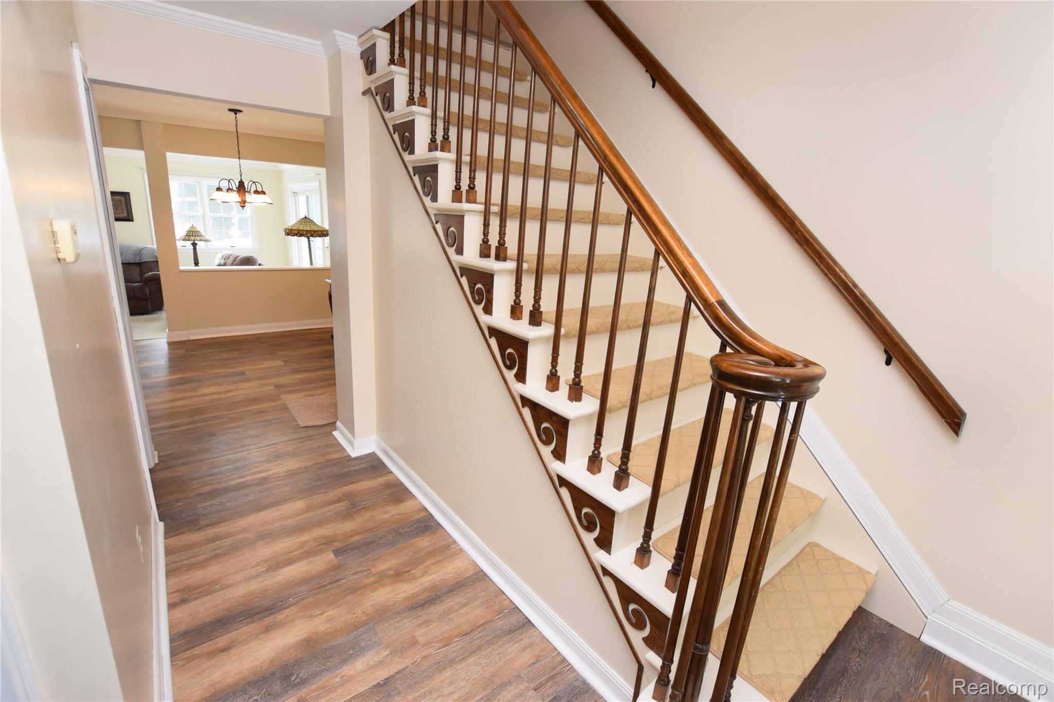 15489 Linden Road Linden, MI 48451 - Photo 18 of 25 Stairs with crown molding, wood finished floors, and a chandelier