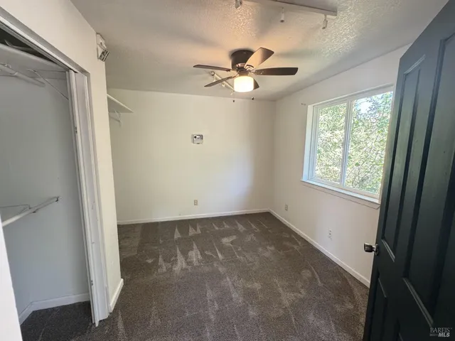 an empty room with windows and fan