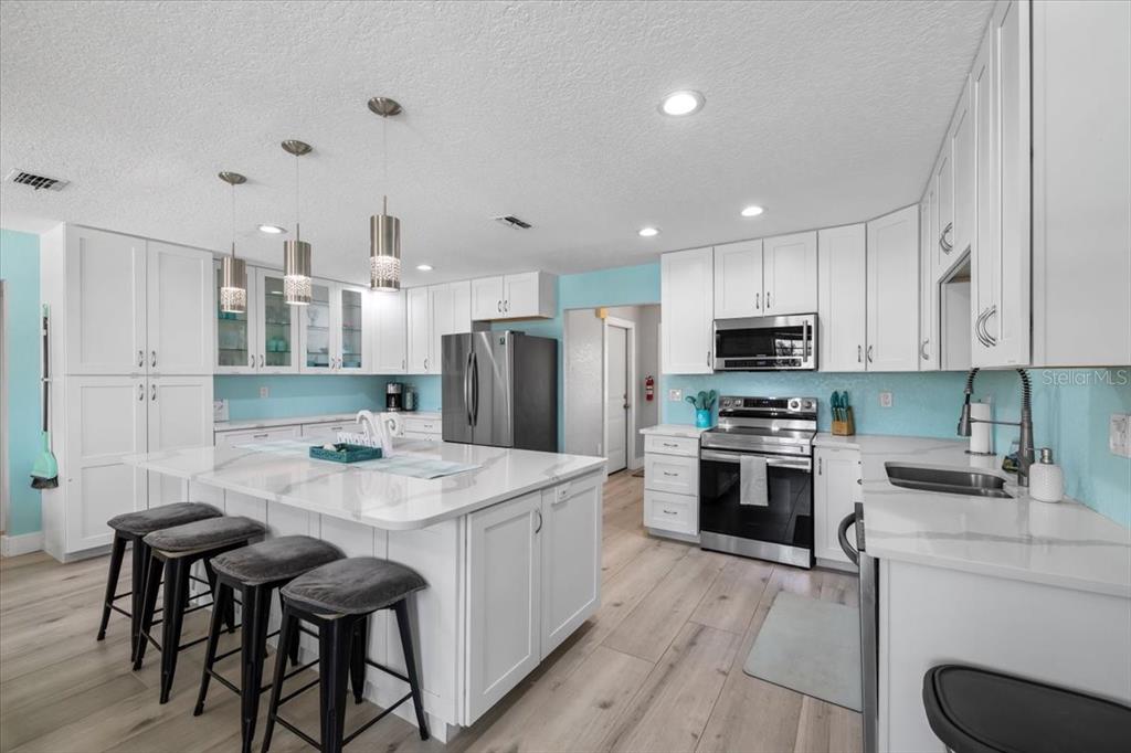 4400 Flexer Drive Hernando Beach, FL 34607 - Photo 5 of 49 a kitchen with stainless steel appliances a stove a sink a refrigerator white cabinets and wooden floor