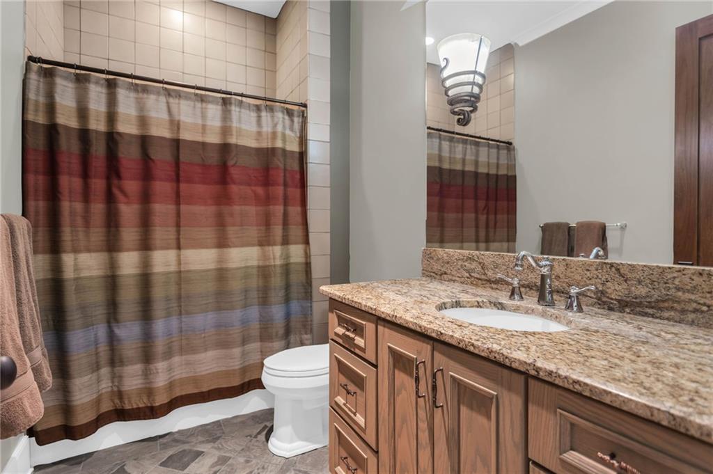 1086 Arbor Hill Road Canton, GA 30115 - Photo 58 of 98 a bathroom with a granite countertop sink a toilet a mirror and shower