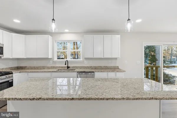 a kitchen with kitchen island granite countertop a sink a counter top space and cabinets
