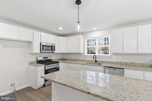 a kitchen with stainless steel appliances granite countertop a sink stove and cabinets