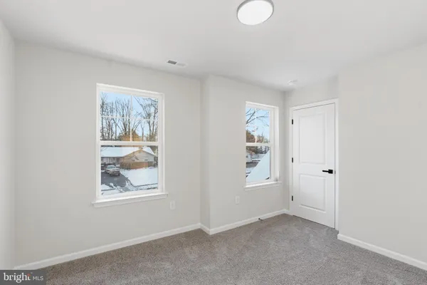 a view of an empty room with window and closet area