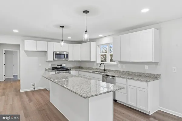 a kitchen with stainless steel appliances granite countertop a sink a stove and white cabinets