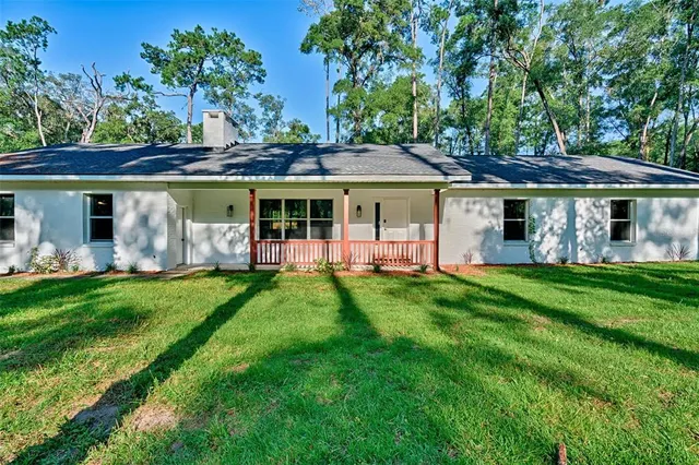a view of a house with a yard potted plants and large tree