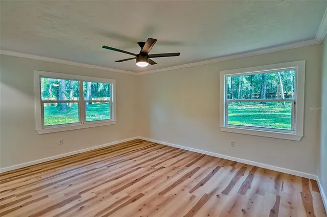 a view of empty room with wooden floor and fan