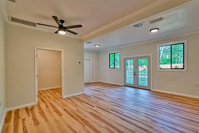 a view of an empty room with window and wooden floor