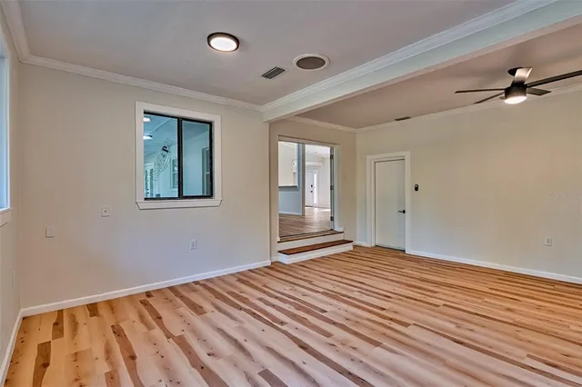 a view of an empty room with wooden floor and a window