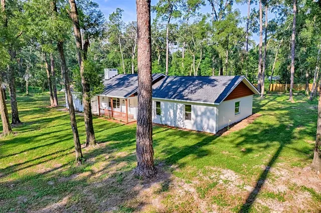 a view of house with backyard and trees