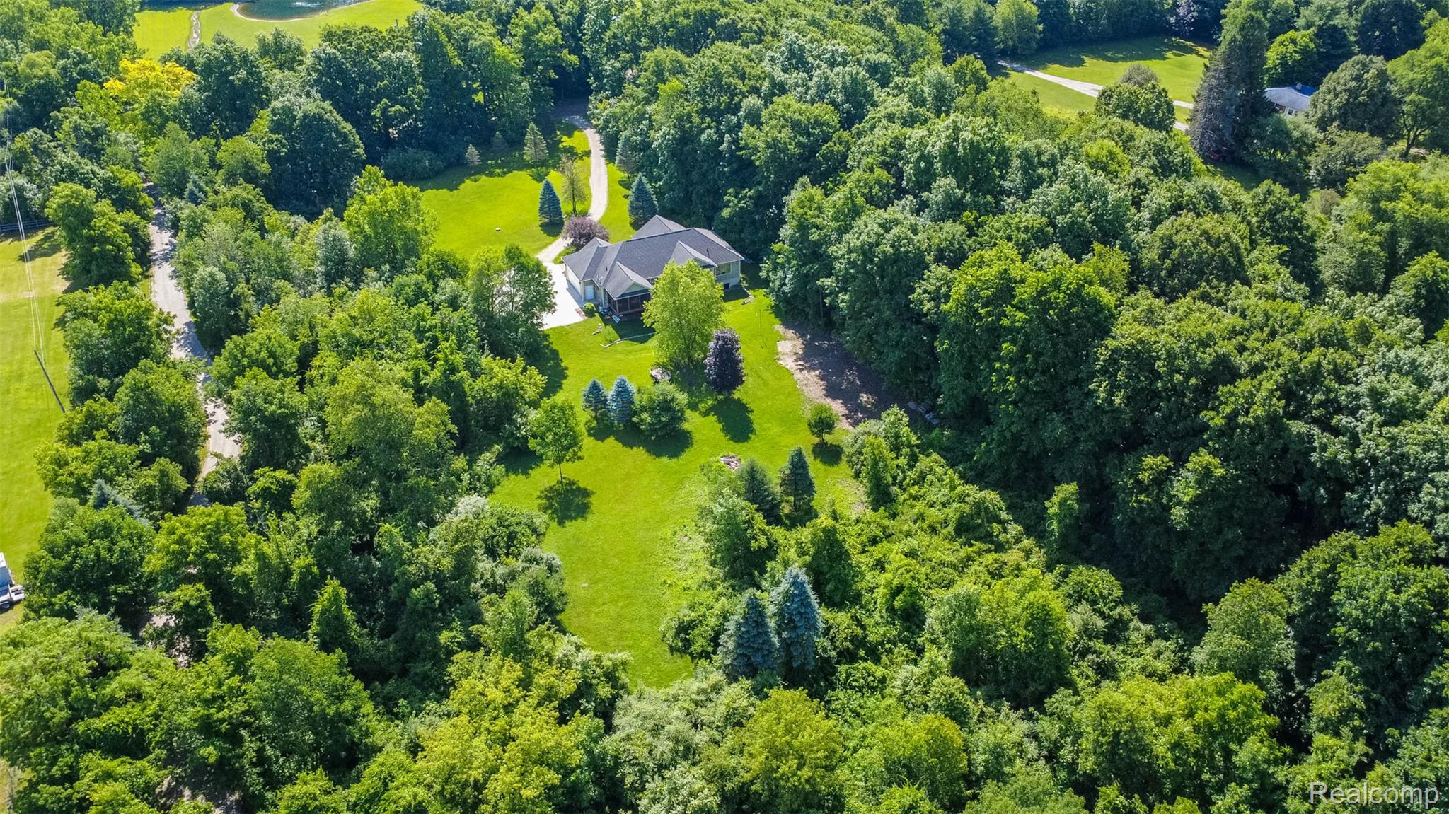 9887 Hadley Road Clarkston, MI 48348 - Photo 51 of 56 Sprawling estate featuring a single-story residence with a dark-pitched roof, surrounded by mature trees and extensive green lawn areas