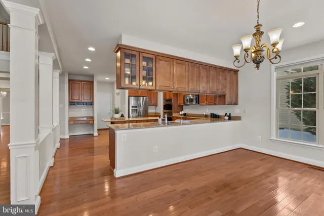 a living room with stainless steel appliances furniture a chandelier and wooden floor