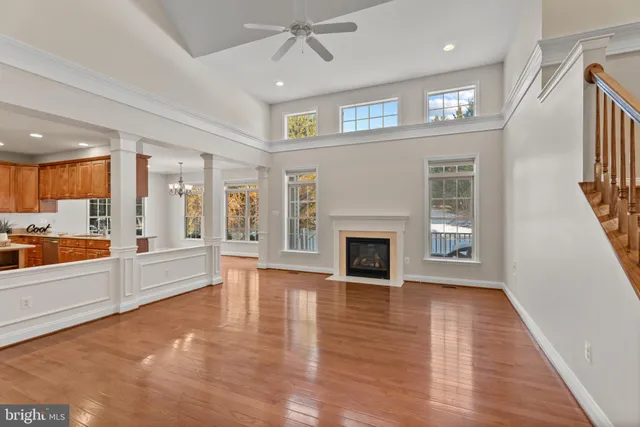 an empty room with wooden floor fireplace and windows