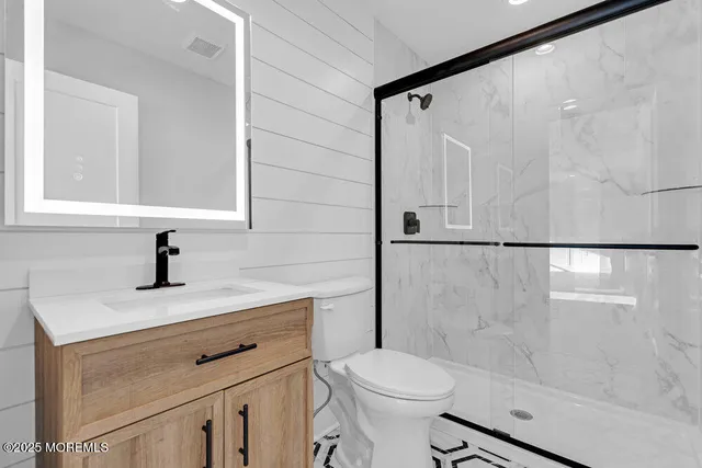a bathroom with a shower sink vanity and toilet