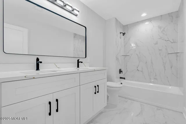 a bathroom with a double vanity sink a toilet and shower