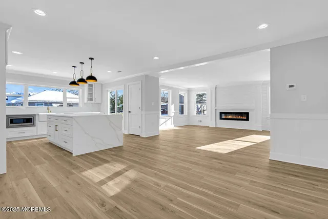 a large white kitchen with kitchen island a stove a wooden floor and a fireplace