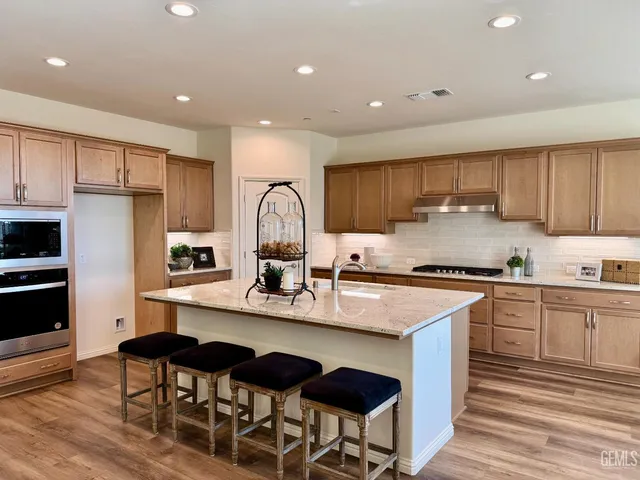 a kitchen with kitchen island granite countertop a sink cabinets and wooden floor