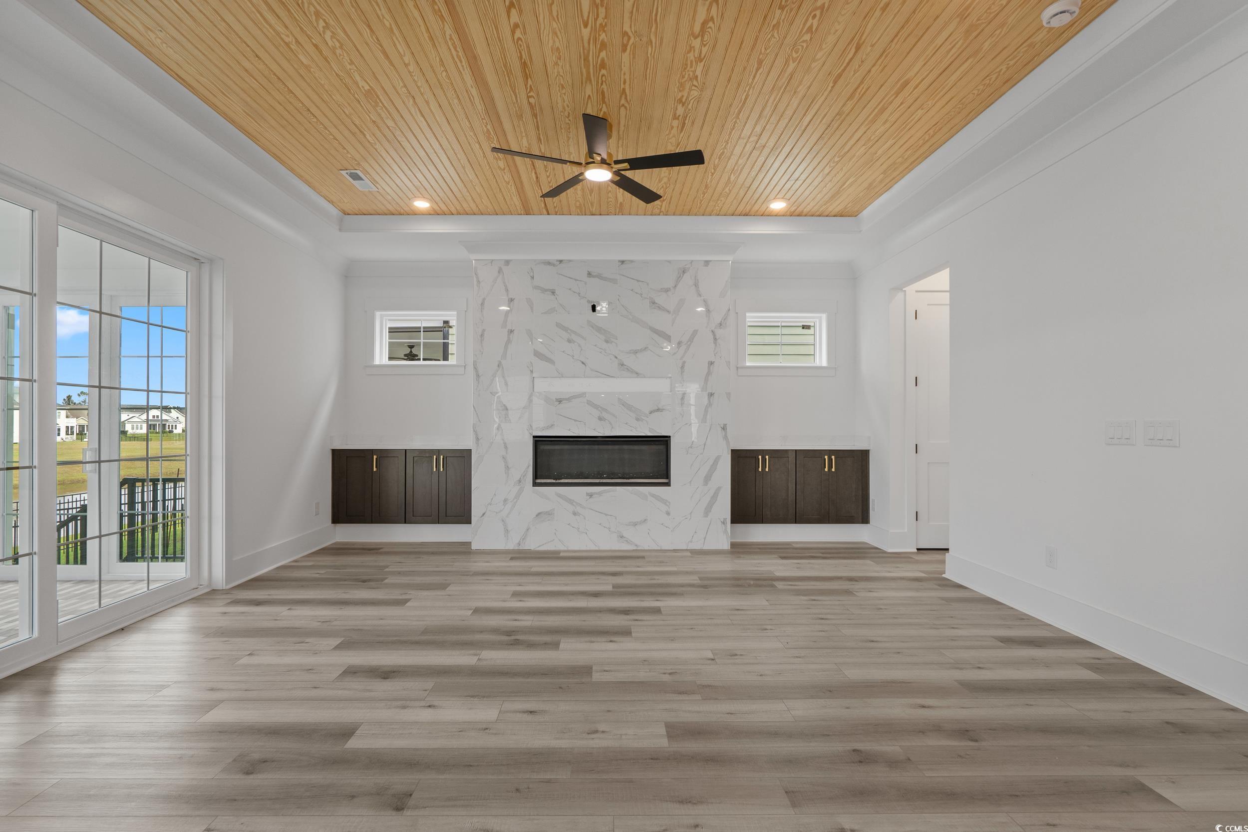 921 Crystal Water Way Myrtle Beach, SC 29579 - Photo 13 of 36 Unfurnished living room with wooden ceiling, a premium fireplace, light wood-type flooring, ceiling fan, and recessed lighting