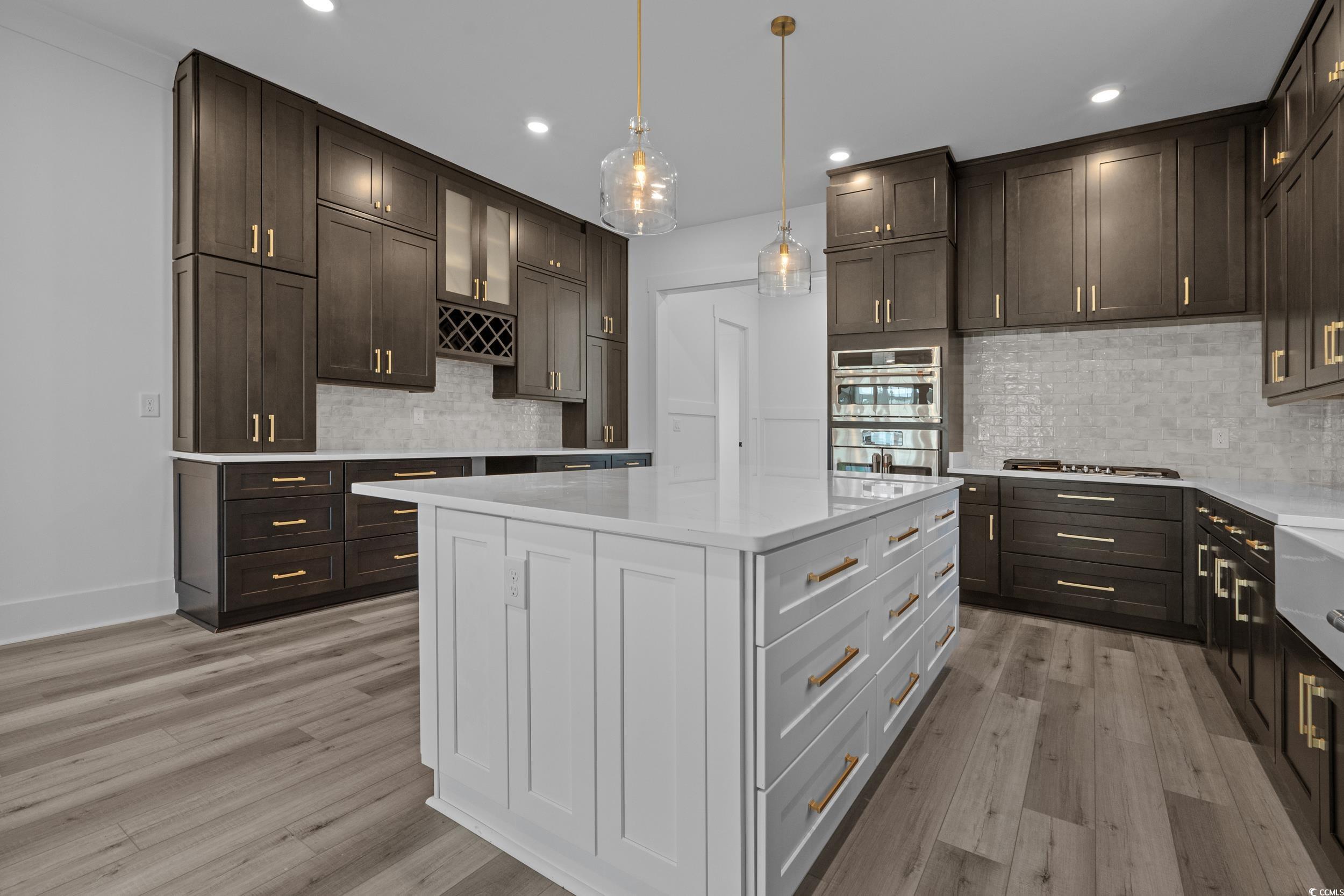 921 Crystal Water Way Myrtle Beach, SC 29579 - Photo 8 of 36 Kitchen featuring white cabinetry, hanging light fixtures, light stone counters, dark brown cabinets, and light wood-style floors