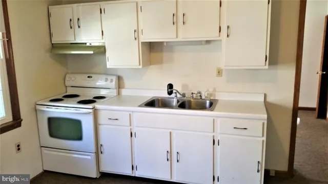 a view of a kitchen with white cabinets and wooden floor
