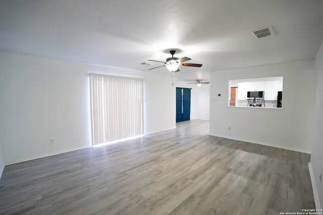 a view of empty room with wooden floor and fan