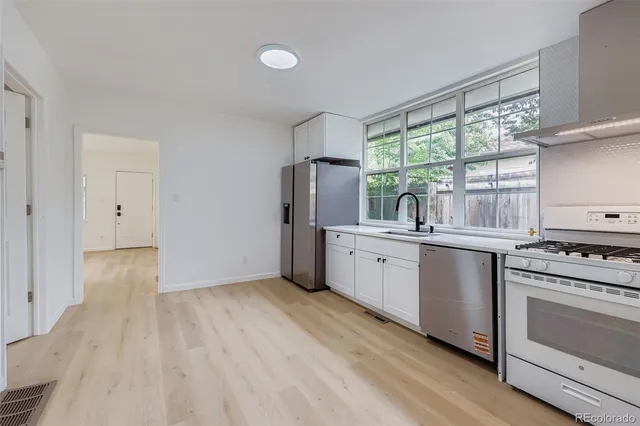 a kitchen with a sink wooden floor and white stainless steel appliances