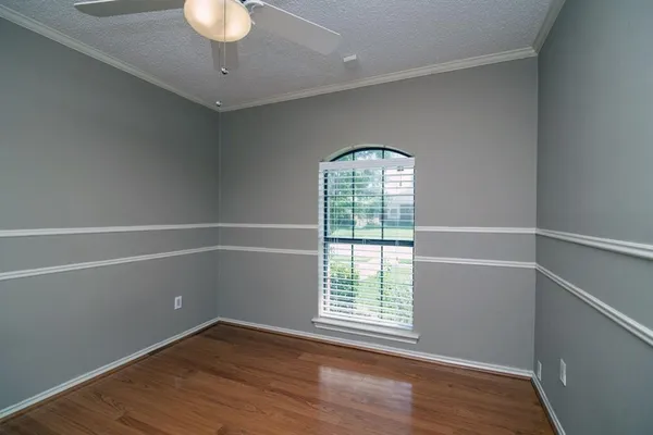 an empty room with wooden floor chandelier and windows