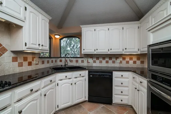 a kitchen with granite countertop a sink dishwasher a stove and a microwave oven