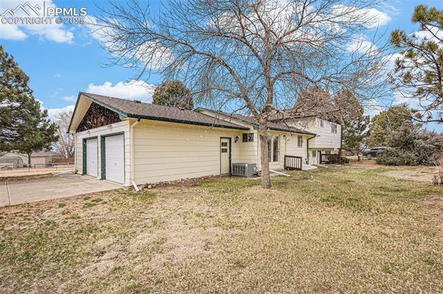 1653 Cragin Road Colorado Springs, CO 80920 - Photo 22 of 27 View of side of home featuring a lawn and roof with shingles