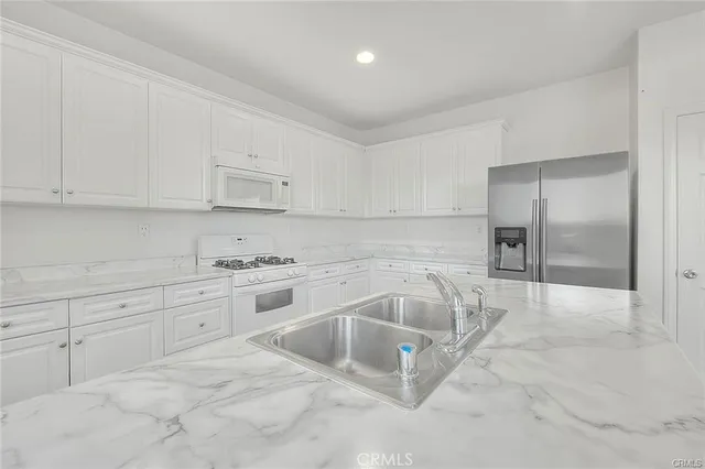a kitchen with granite countertop a sink and white cabinets