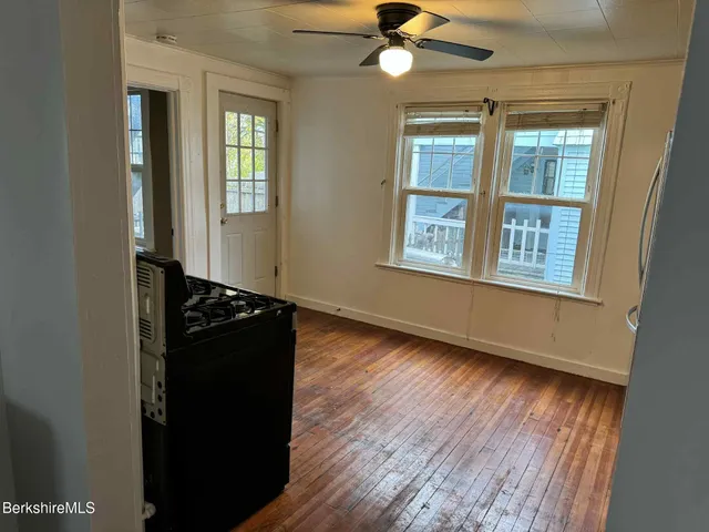 an empty room with wooden floor closet and windows