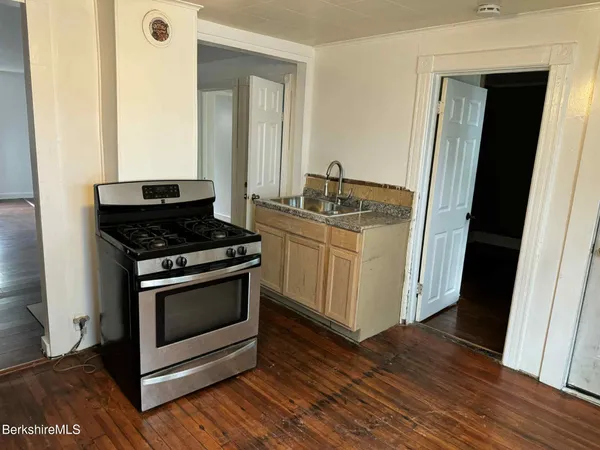 a kitchen with a stove and a wooden floor