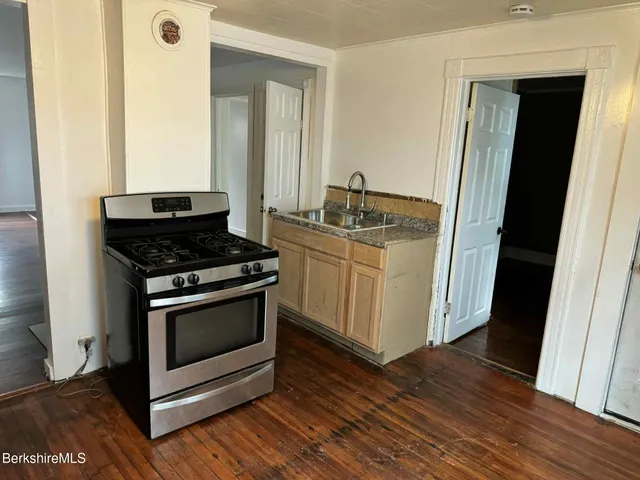 a kitchen with a stove and a wooden floor