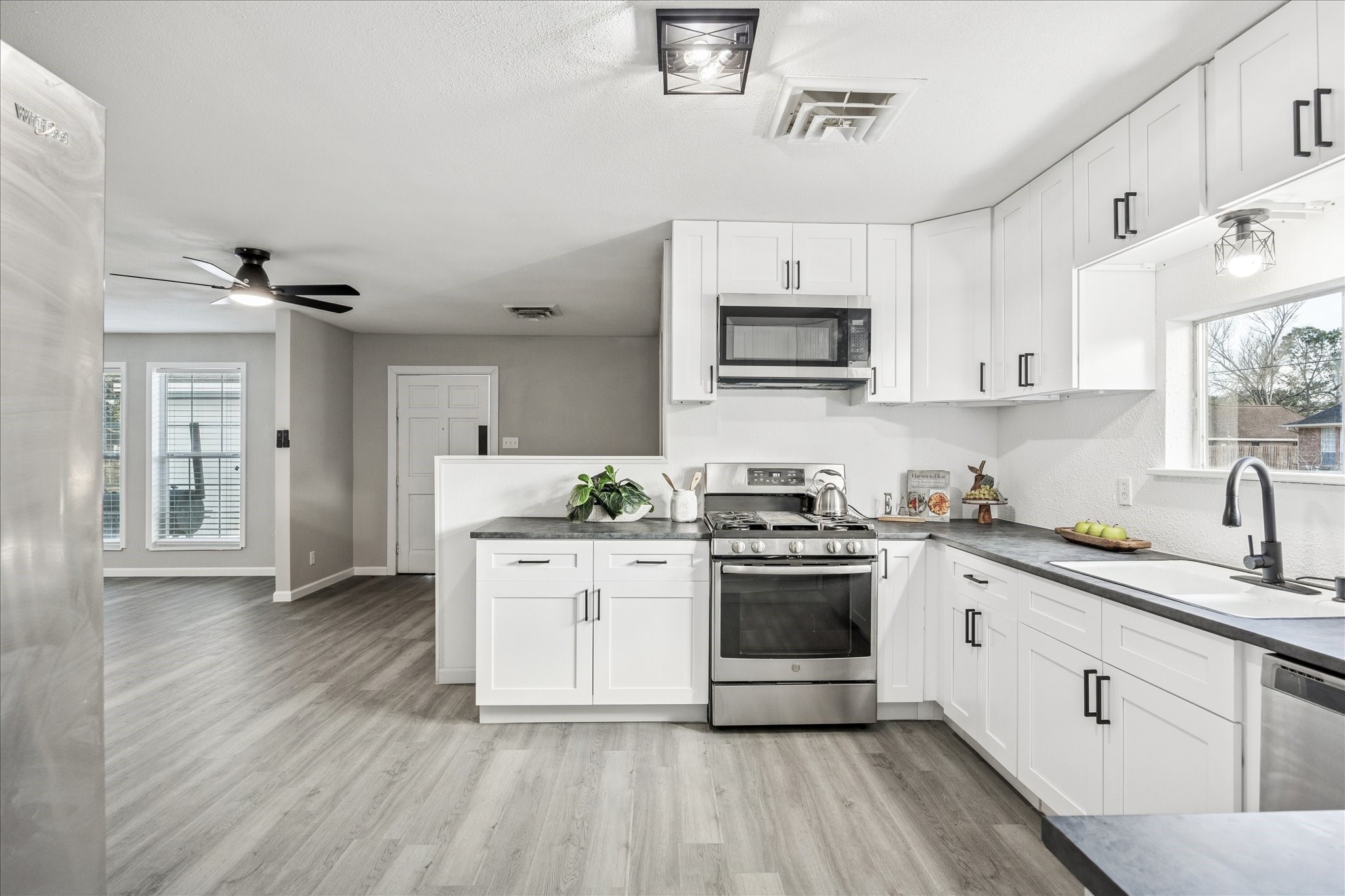 11910 11th Street Santa Fe, TX 77510 - Photo 4 of 30 a kitchen with stainless steel appliances granite countertop a stove a sink dishwasher and a microwave oven with white cabinets