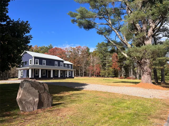 a front view of a house with a yard covered with snow and trees