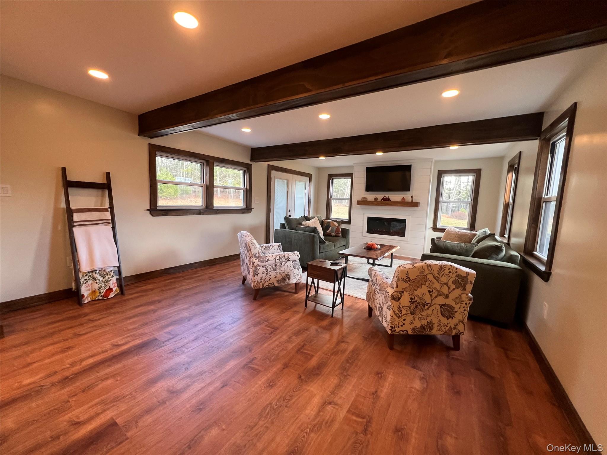 79 Dexheimer Road Narrowsburg, NY 12764 - Photo 11 of 29 Living area with beamed ceiling, recessed lighting, a glass covered fireplace, and dark wood-style floors