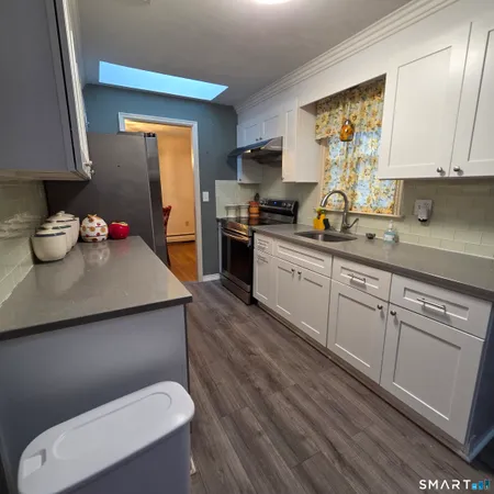 a kitchen with stainless steel appliances a sink cabinets and wooden floor