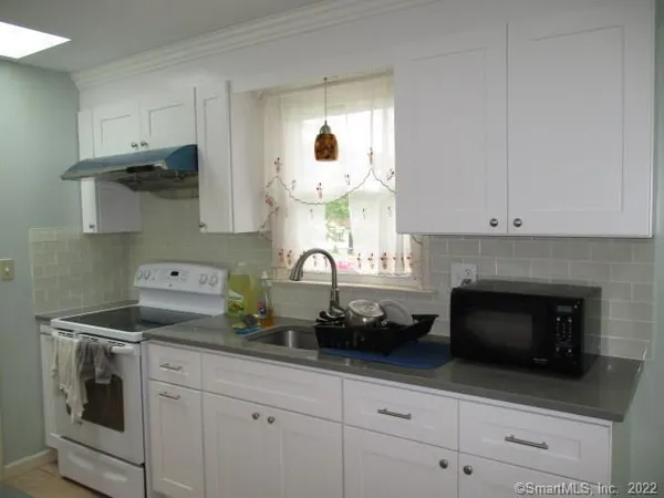a kitchen with white cabinets and appliances