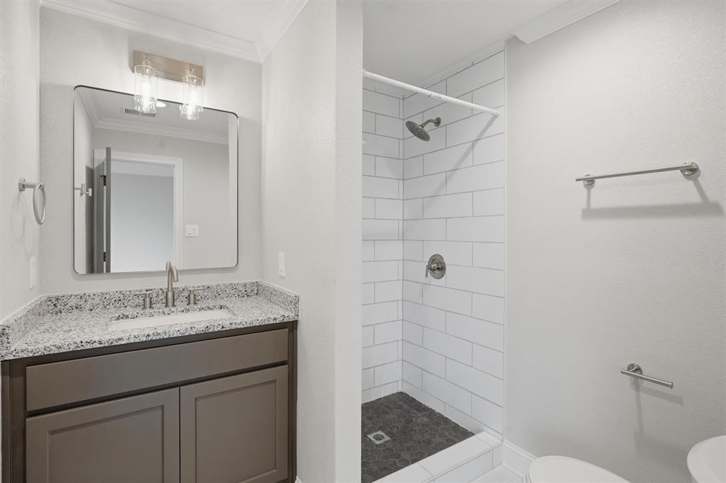 9121 Bontura Road Granbury, TX 76049 - Photo 20 of 40 Bathroom vanity featuring a granite countertop with an undermount sink, brushed nickel faucet, and a contemporary mirror