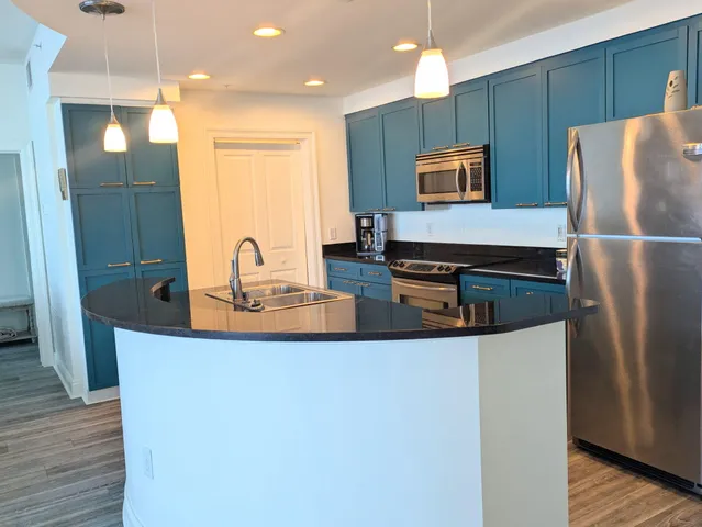 a kitchen with stainless steel appliances a refrigerator a sink a stove a microwave and wooden floor