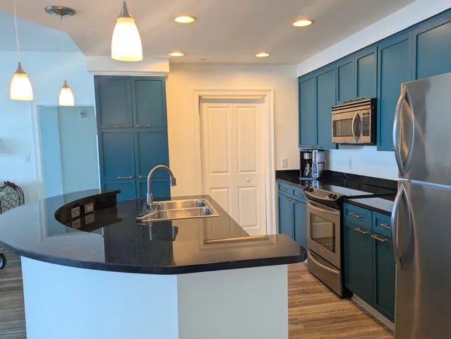 a kitchen with kitchen island granite countertop a sink stove and refrigerator