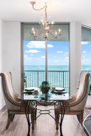a view of a dining room with furniture a chandelier and large windows