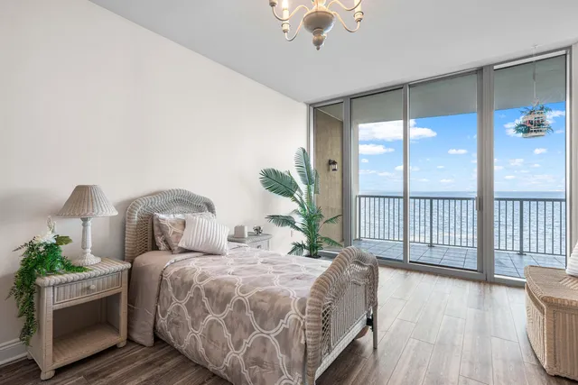 a bedroom with a large bed and a large window with wooden floor
