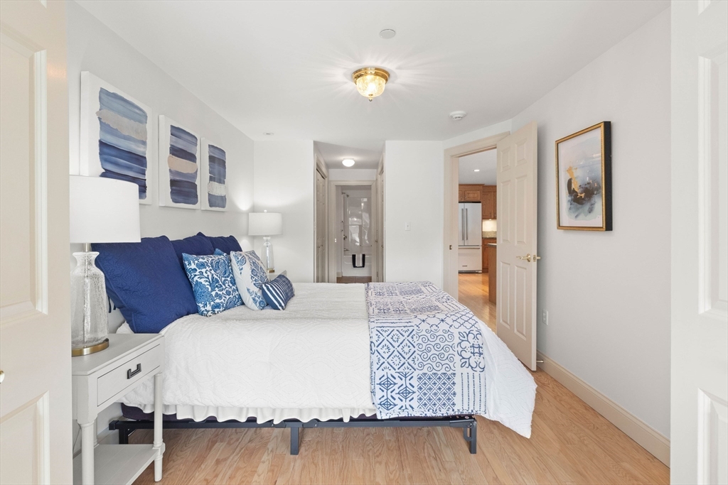 60 Merrimac Street, Unit 907 Amesbury, MA 01913 - Photo 18 of 23 a large bedroom with a bed and wooden floor