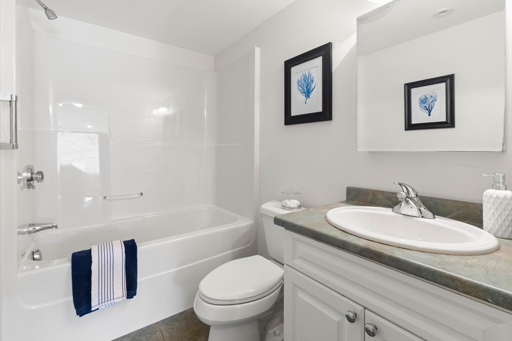 60 Merrimac Street, Unit 907 Amesbury, MA 01913 - Photo 20 of 23 a bathroom with a granite countertop sink mirror toilet and bathtub