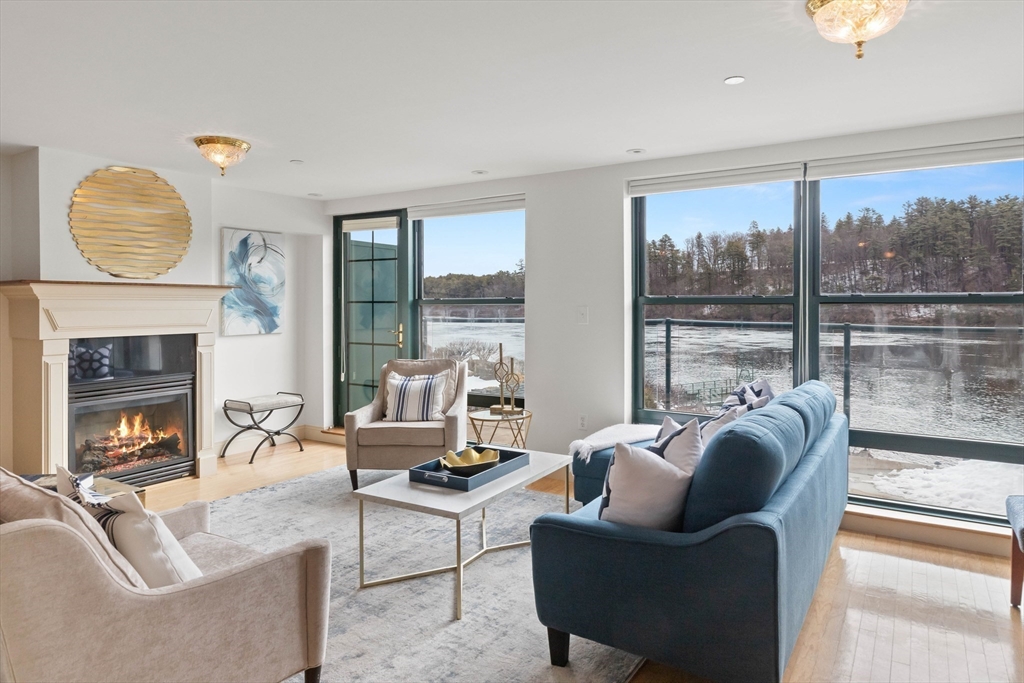 60 Merrimac Street, Unit 907 Amesbury, MA 01913 - Photo 4 of 23 a living room with furniture a fireplace and floor to ceiling windows